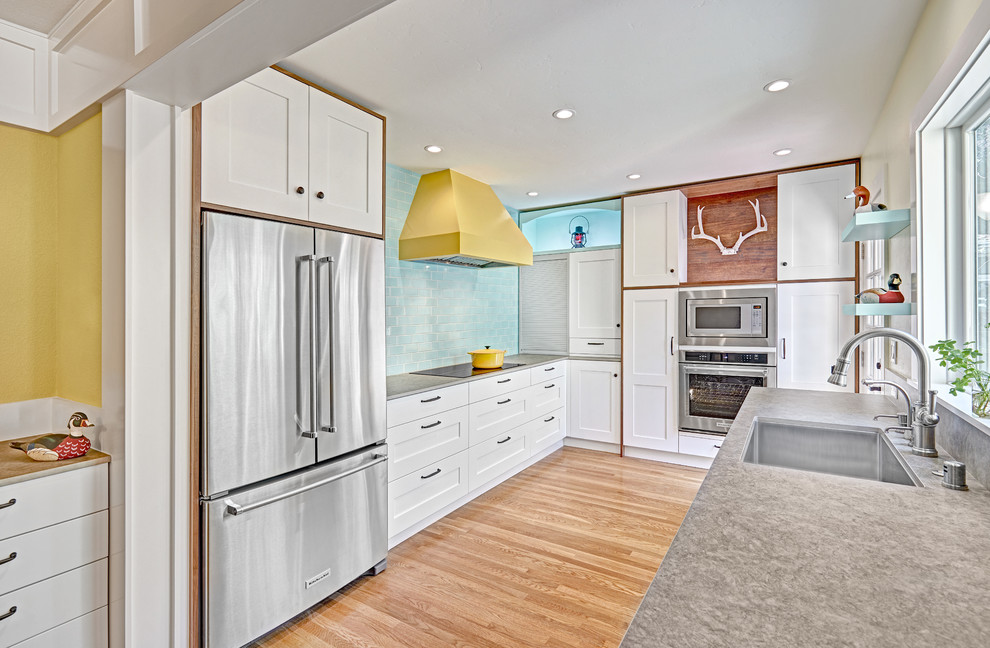 Foto på ett mellanstort amerikanskt kök, med en undermonterad diskho, luckor med infälld panel, vita skåp, bänkskiva i kvarts, blått stänkskydd, stänkskydd i keramik, rostfria vitvaror och mellanmörkt trägolv