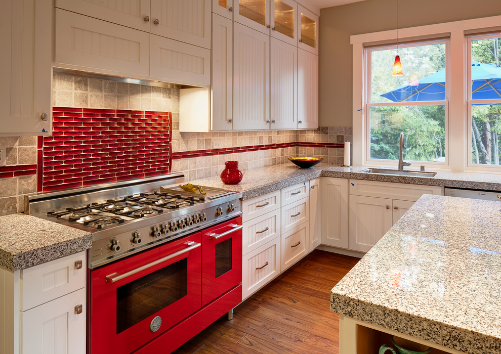 Inspiration för mellanstora amerikanska kök, med en undermonterad diskho, vita skåp, granitbänkskiva, rött stänkskydd, stänkskydd i glaskakel, färgglada vitvaror, mellanmörkt trägolv, en köksö, brunt golv och luckor med infälld panel