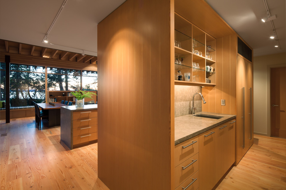 Moderne Wohnküche mit Unterbauwaschbecken, flächenbündigen Schrankfronten, hellbraunen Holzschränken, Elektrogeräten mit Frontblende, braunem Holzboden und Kücheninsel in Seattle
