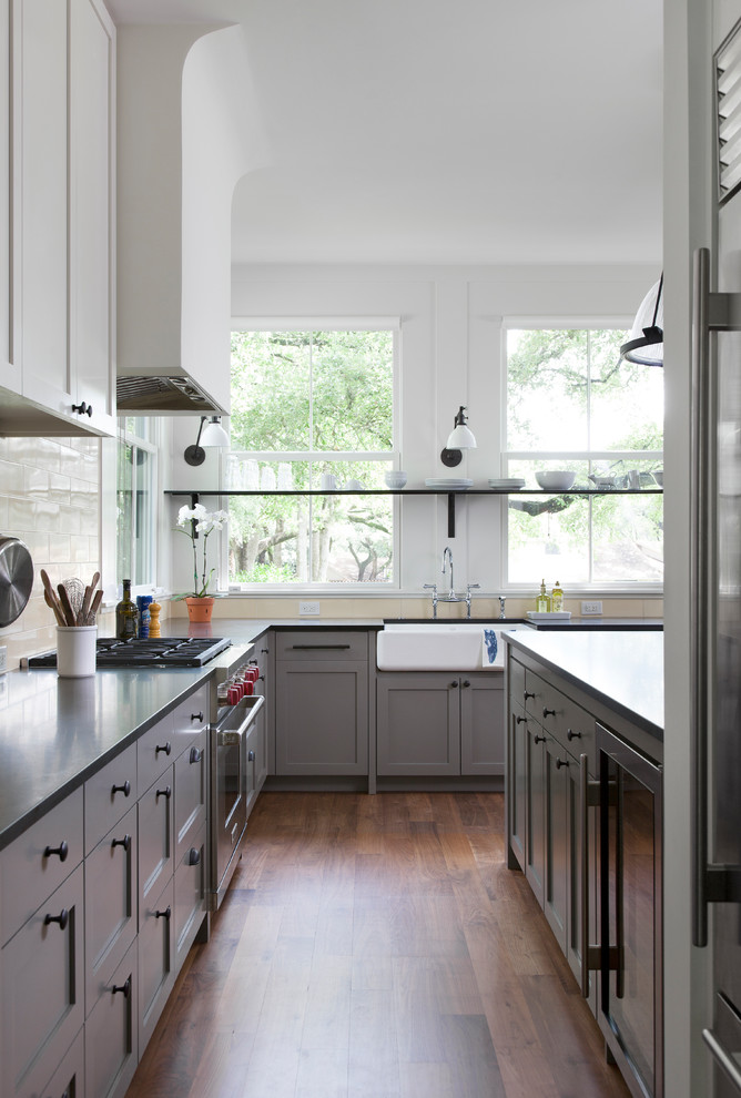 Cette photo montre une grande cuisine parallèle chic avec un placard à porte shaker, des portes de placard grises, un plan de travail en granite, une crédence jaune, un sol en bois brun et plan de travail noir.