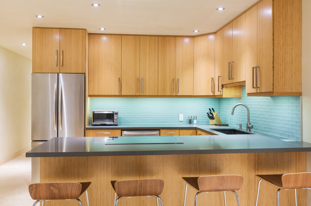 Retro Wohnküche ohne Insel mit flächenbündigen Schrankfronten, hellen Holzschränken, Küchenrückwand in Blau, Rückwand aus Glasfliesen und Küchengeräten aus Edelstahl in Los Angeles
