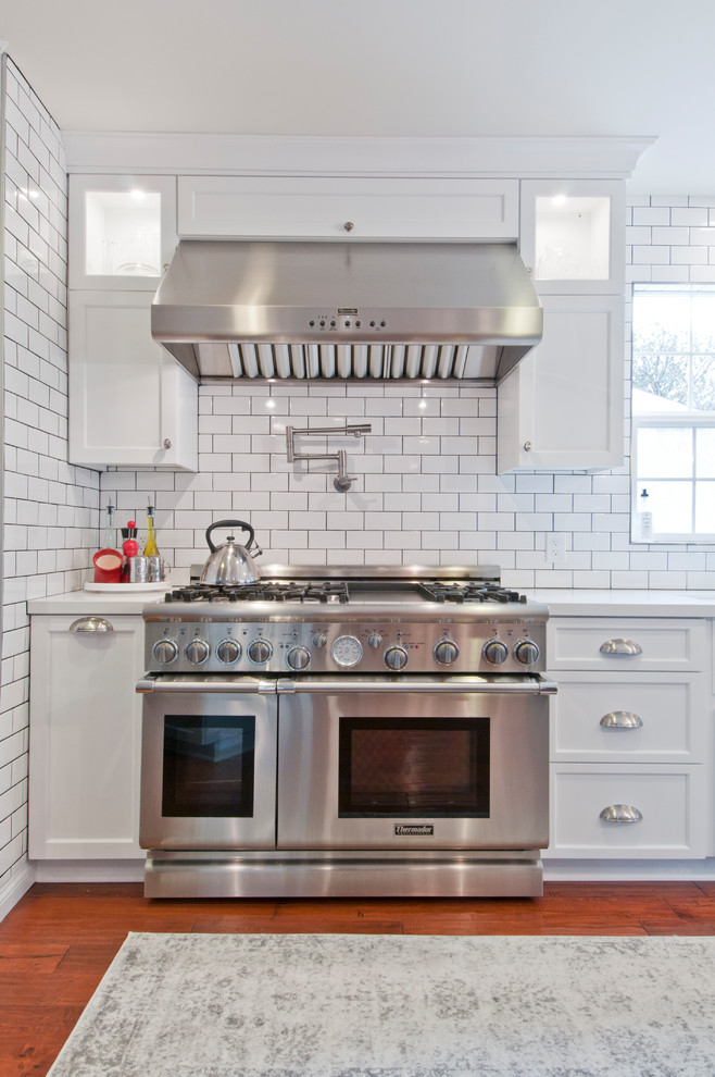 Exempel på ett stort klassiskt vit vitt kök med öppen planlösning, med en rustik diskho, skåp i shakerstil, vita skåp, bänkskiva i kvarts, vitt stänkskydd, stänkskydd i tunnelbanekakel, rostfria vitvaror, mellanmörkt trägolv, flera köksöar och brunt golv