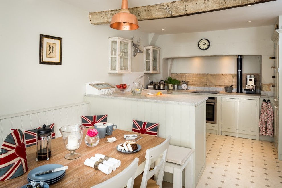 This is an example of a medium sized country u-shaped kitchen/diner in Wiltshire with a belfast sink, shaker cabinets, white cabinets, marble worktops, beige splashback, lino flooring and beige floors.
