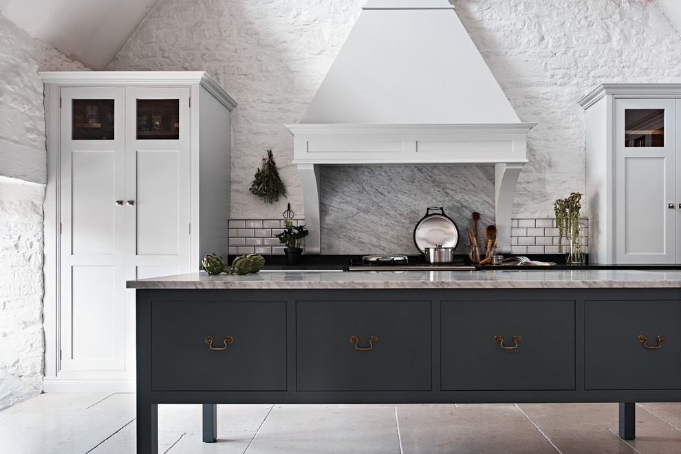 Photo of a large country l-shaped enclosed kitchen in Wiltshire with recessed-panel cabinets, white cabinets, marble worktops, grey splashback, travertine flooring, an island and beige floors.