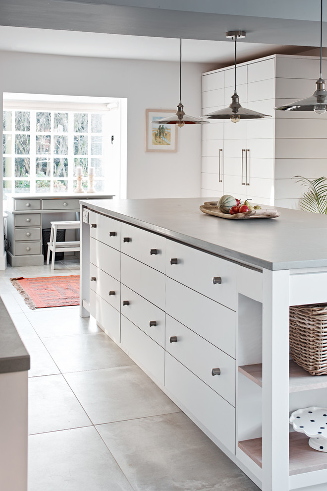 Foto de cocina contemporánea con armarios con paneles lisos, puertas de armario blancas, encimera de cemento y una isla