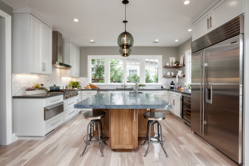 Design ideas for a large contemporary u-shaped kitchen in San Francisco with shaker cabinets, white cabinets, stainless steel appliances, light hardwood flooring, an island and matchstick tiled splashback.