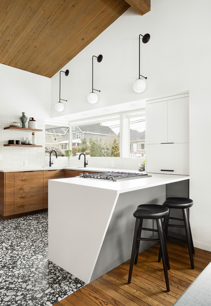 Modern inredning av ett litet vit vitt kök, med en undermonterad diskho, släta luckor, skåp i mörkt trä, bänkskiva i kvarts, vitt stänkskydd, stänkskydd i keramik, integrerade vitvaror, terrazzogolv och svart golv