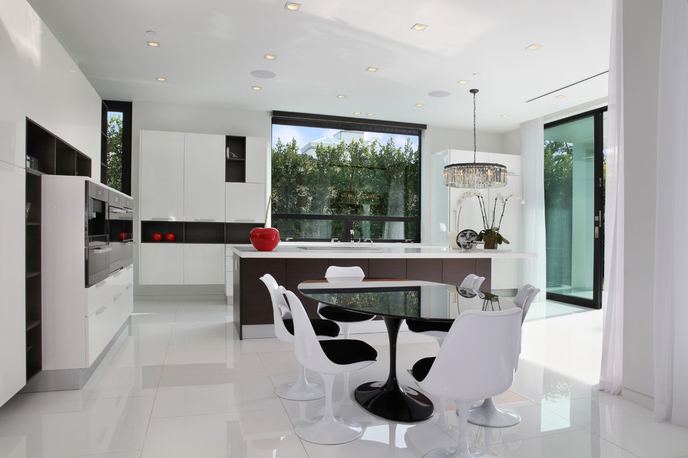 Inspiration for a large modern l-shaped kitchen/diner in Los Angeles with a built-in sink, flat-panel cabinets, white cabinets, marble worktops, glass sheet splashback, stainless steel appliances, an island and white floors.