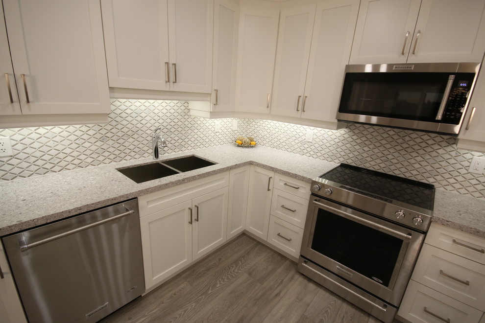 Foto di una cucina design di medie dimensioni con lavello sottopiano, ante in stile shaker, ante bianche, top in quarzo composito, paraspruzzi giallo e elettrodomestici in acciaio inossidabile