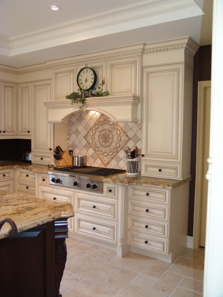 Inredning av ett klassiskt stort kök, med luckor med upphöjd panel, skåp i slitet trä, granitbänkskiva, beige stänkskydd, stänkskydd i stenkakel, rostfria vitvaror, travertin golv, en köksö och en undermonterad diskho
