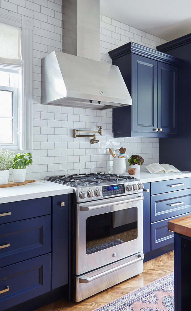 Idee per una cucina tradizionale chiusa e di medie dimensioni con lavello stile country, ante blu, top in quarzite, paraspruzzi bianco, pavimento in legno massello medio e top bianco