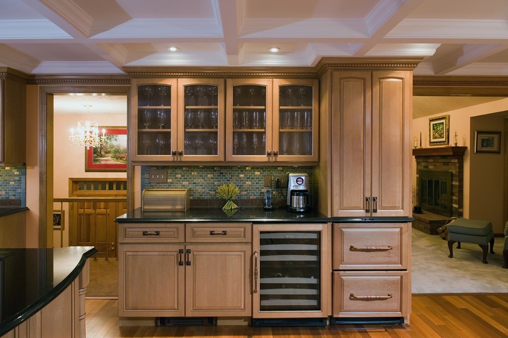 Klassische Küche mit hellbraunen Holzschränken, Granit-Arbeitsplatte, Küchenrückwand in Grün, Rückwand aus Keramikfliesen, Elektrogeräten mit Frontblende, braunem Holzboden, Kücheninsel und profilierten Schrankfronten in Boston