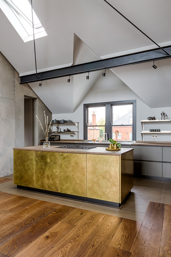 This is an example of a medium sized contemporary galley open plan kitchen in London with flat-panel cabinets, distressed cabinets, wood worktops, stainless steel appliances, dark hardwood flooring, an island and multi-coloured floors.