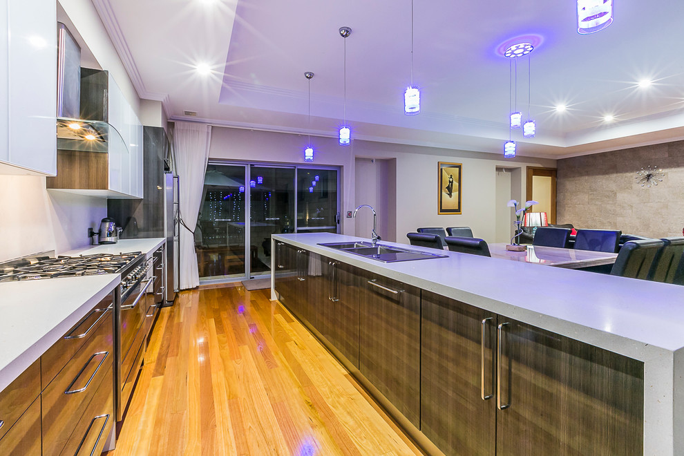 Example of a large trendy galley medium tone wood floor eat-in kitchen design in Perth with a drop-in sink, flat-panel cabinets, dark wood cabinets, quartz countertops, metallic backsplash, glass sheet backsplash, stainless steel appliances and an island