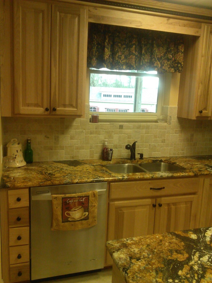 Example of a mid-sized mountain style l-shaped ceramic tile open concept kitchen design in Birmingham with a drop-in sink, recessed-panel cabinets, light wood cabinets, granite countertops, beige backsplash, stone tile backsplash, stainless steel appliances and an island