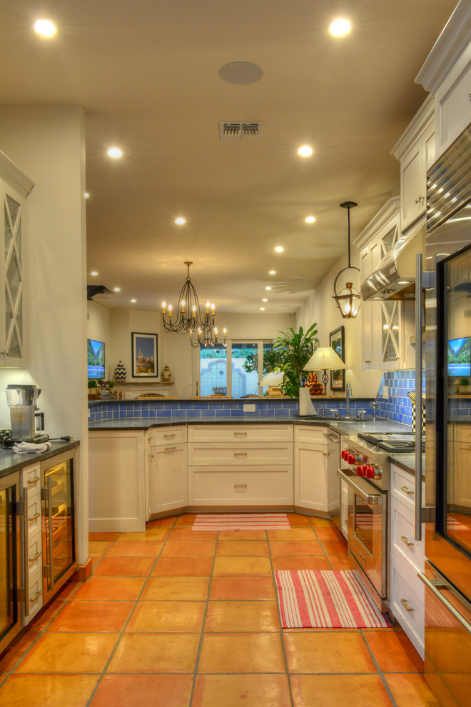 Foto di una cucina tradizionale di medie dimensioni con ante in stile shaker, ante bianche, paraspruzzi blu, elettrodomestici in acciaio inossidabile, pavimento in terracotta e top in saponaria