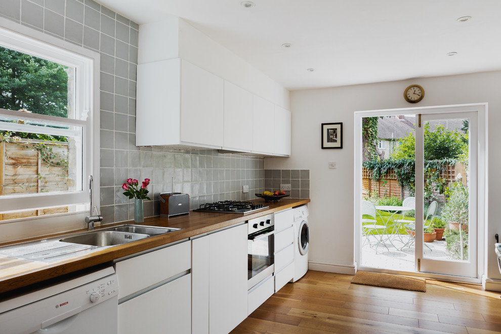 ケンブリッジシャーにある北欧スタイルのおしゃれなI型キッチン (ドロップインシンク、フラットパネル扉のキャビネット、白いキャビネット、木材カウンター、無垢フローリング、アイランドなし、茶色い床、茶色いキッチンカウンター) の写真