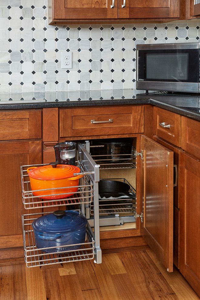 Foto på ett vintage l-kök, med en undermonterad diskho, skåp i shakerstil, skåp i mellenmörkt trä, granitbänkskiva, flerfärgad stänkskydd, stänkskydd i stenkakel, rostfria vitvaror, ljust trägolv och en köksö