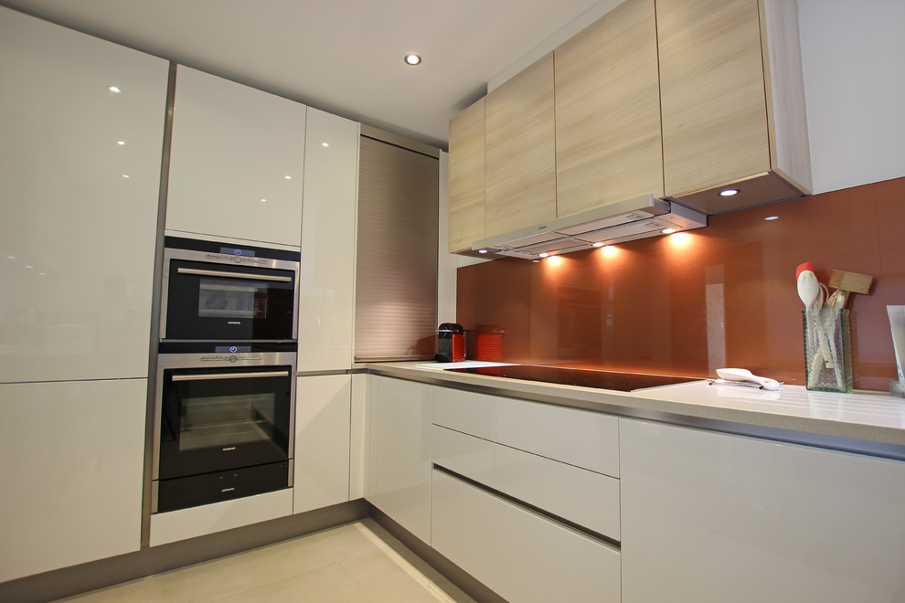 ロンドンにあるコンテンポラリースタイルのおしゃれなキッチン (白いキャビネット、オレンジのキッチンパネル、ガラス板のキッチンパネル) の写真