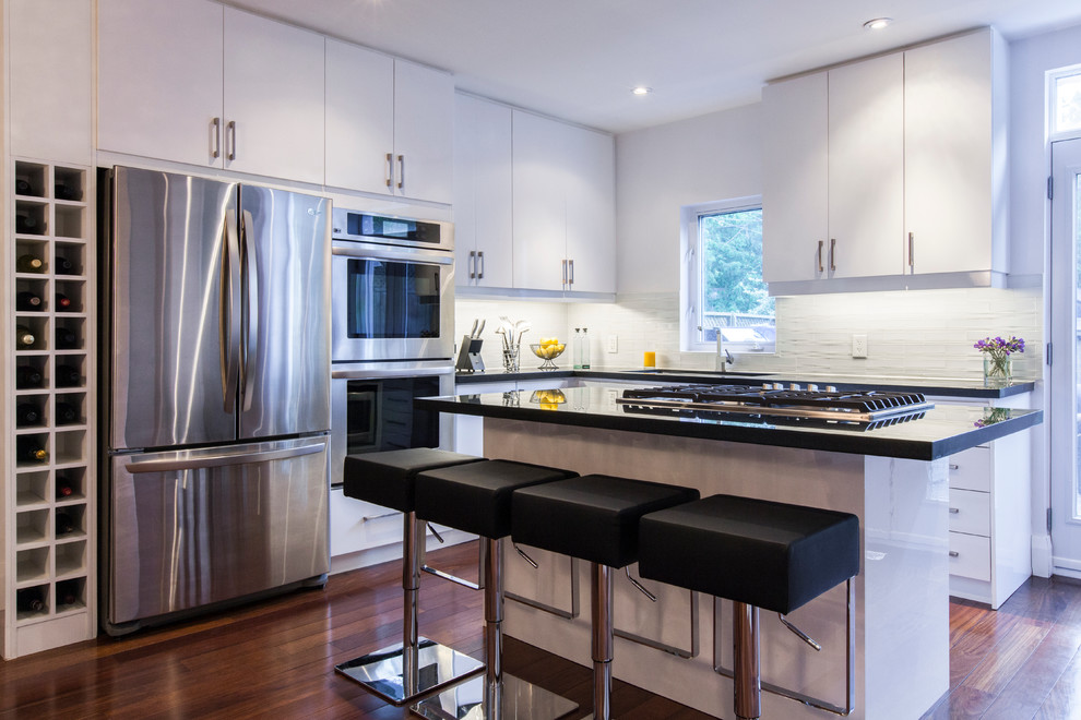 Example of a trendy kitchen design in Toronto with flat-panel cabinets, white cabinets, white backsplash and stainless steel appliances