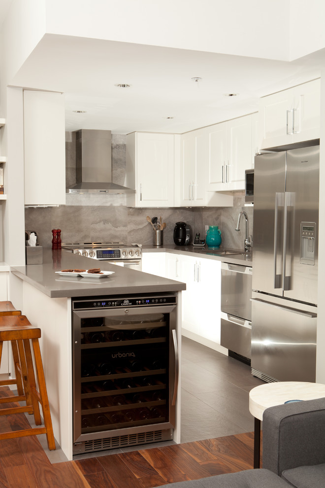 Cette image montre une cuisine design avec des portes de placard blanches et une crédence grise.