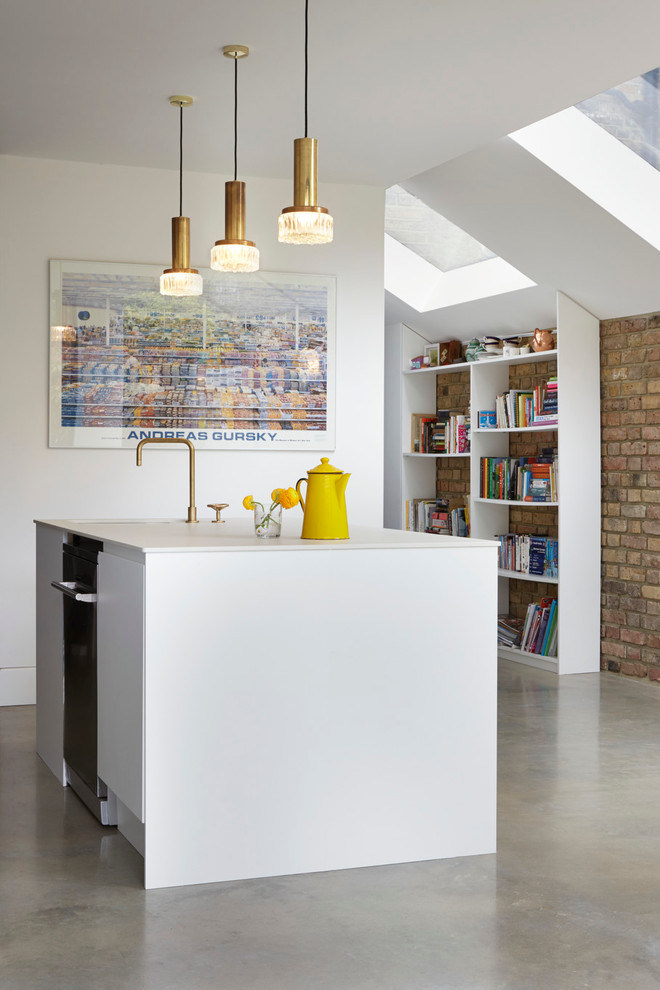 Photo of a small contemporary single-wall open plan kitchen in Other with a belfast sink, flat-panel cabinets, white cabinets, composite countertops, white splashback, glass sheet splashback, white appliances, concrete flooring and an island.