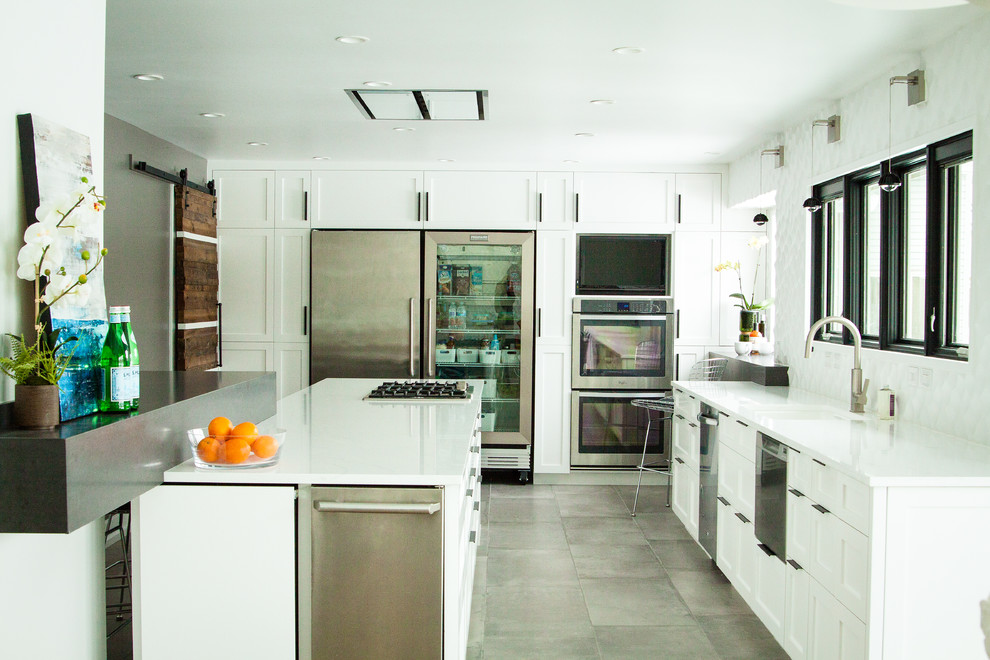 Cette image montre une cuisine américaine design avec un placard à porte shaker, des portes de placard blanches et îlot.