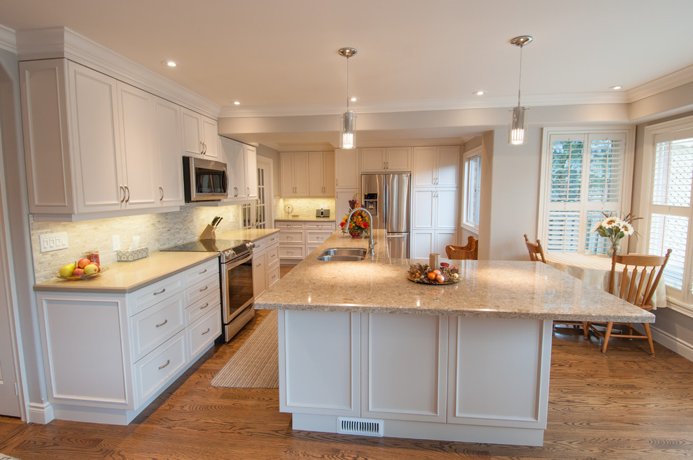 Mid-sized elegant u-shaped medium tone wood floor open concept kitchen photo in Toronto with a double-bowl sink, recessed-panel cabinets, white cabinets, granite countertops, beige backsplash, stone tile backsplash, stainless steel appliances and an island