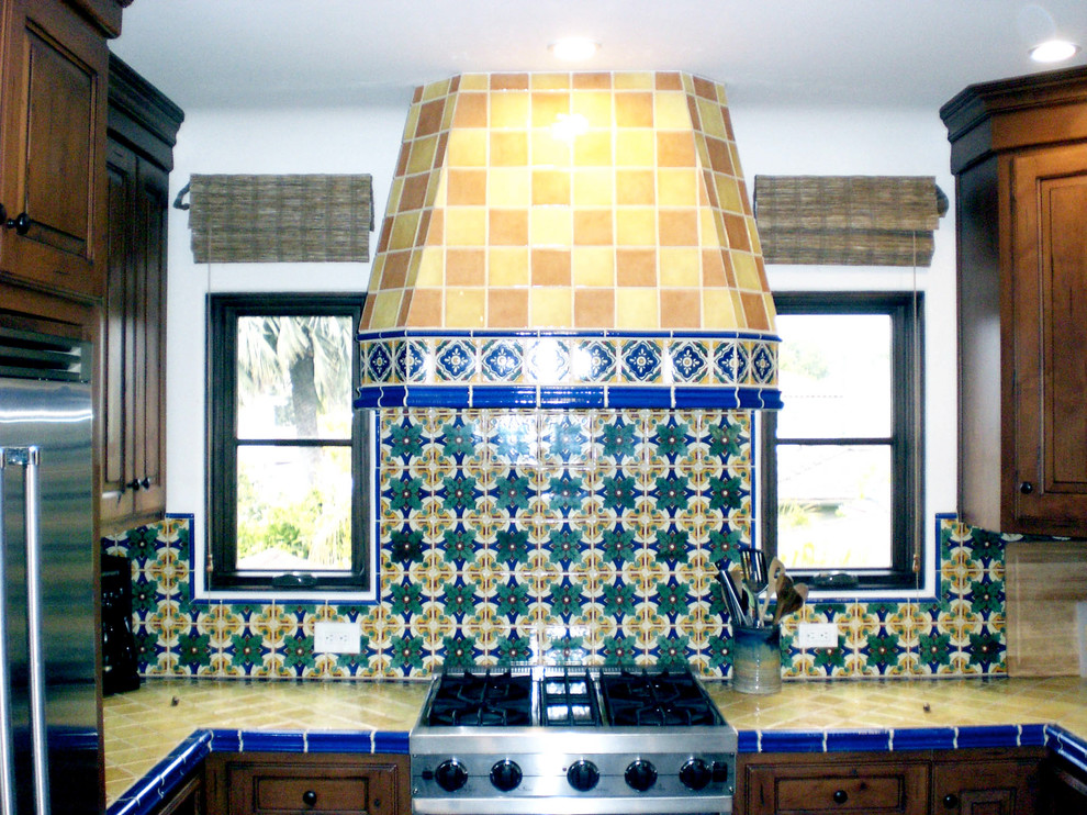 Inspiration for a mid-sized mediterranean u-shaped eat-in kitchen remodel in Santa Barbara with no island, dark wood cabinets, tile countertops, stainless steel appliances, a drop-in sink, multicolored backsplash and mosaic tile backsplash