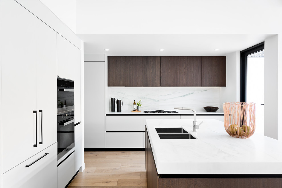 Foto di una cucina design con lavello a doppia vasca, ante lisce, paraspruzzi bianco, elettrodomestici neri, parquet chiaro e top bianco