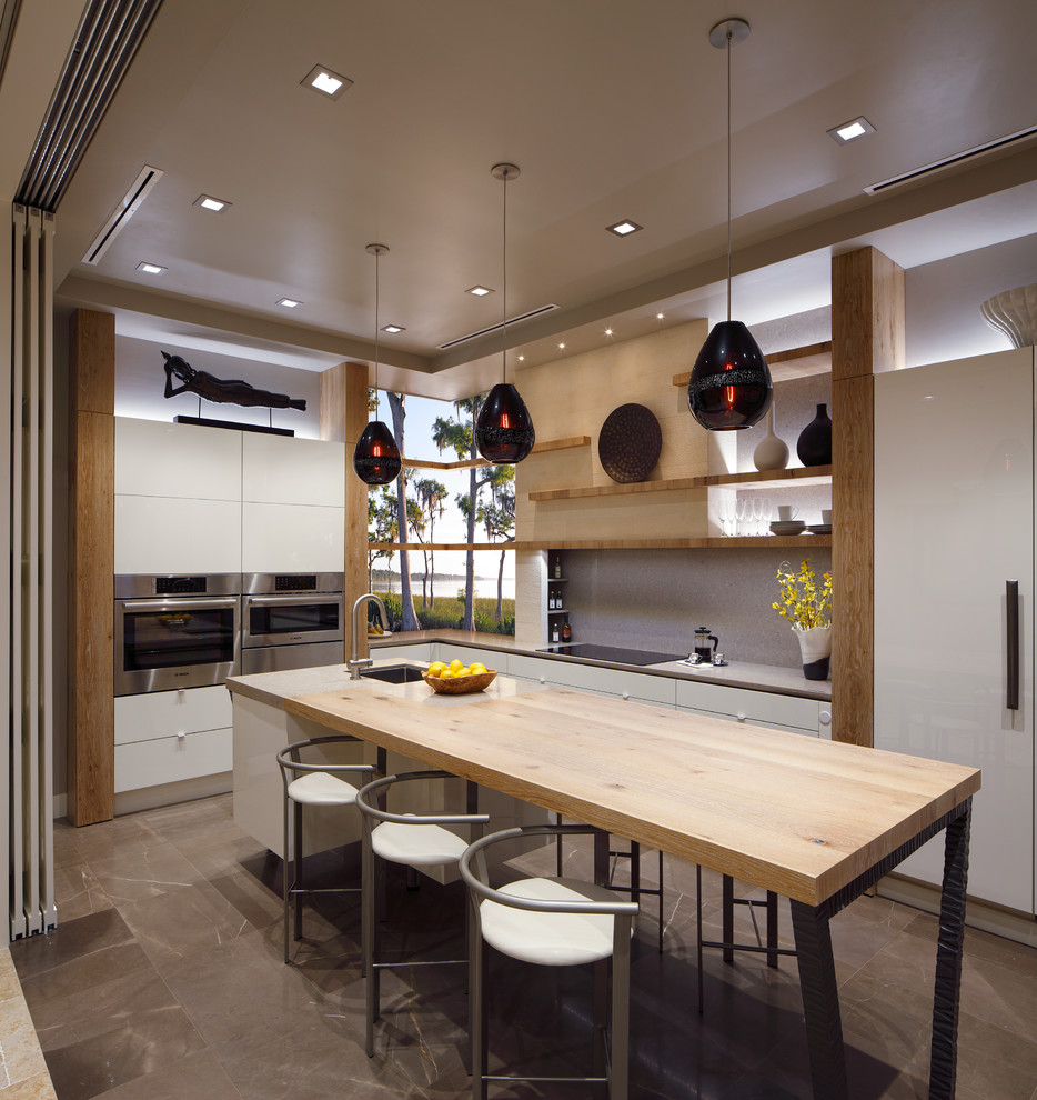 Ejemplo de cocina contemporánea con armarios con paneles lisos, salpicadero verde, electrodomésticos de acero inoxidable, una isla y puertas de armario blancas