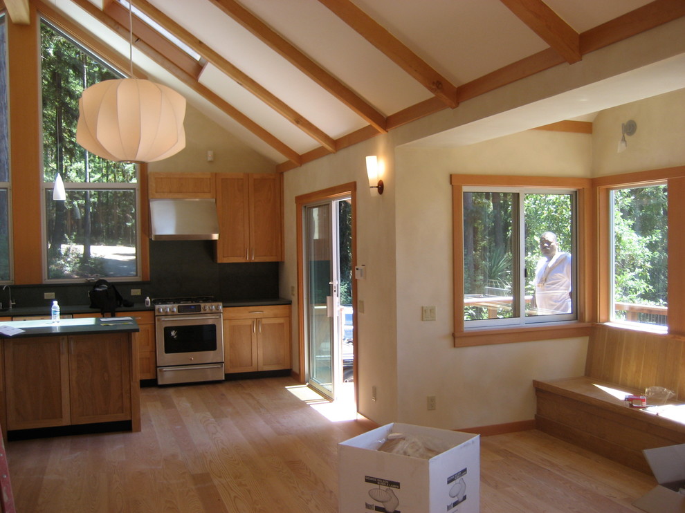 Cette photo montre une cuisine éclectique avec un électroménager en acier inoxydable et un sol en bois brun.