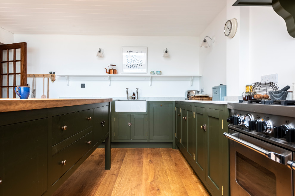 Inspiration for a classic kitchen in Cornwall with a belfast sink, shaker cabinets, green cabinets, engineered stone countertops, stainless steel appliances, medium hardwood flooring and white worktops.