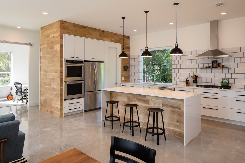 Foto på ett mellanstort lantligt kök, med en undermonterad diskho, släta luckor, vita skåp, bänkskiva i koppar, vitt stänkskydd, stänkskydd i porslinskakel, rostfria vitvaror, betonggolv och en köksö
