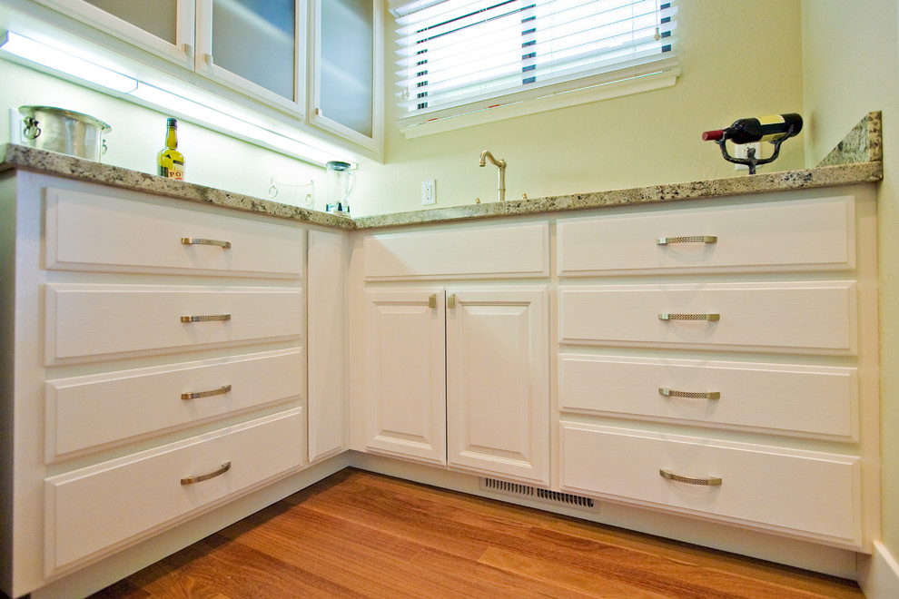 Large trendy u-shaped medium tone wood floor enclosed kitchen photo in San Francisco with an undermount sink, raised-panel cabinets, white cabinets, granite countertops, green backsplash, stone slab backsplash and stainless steel appliances