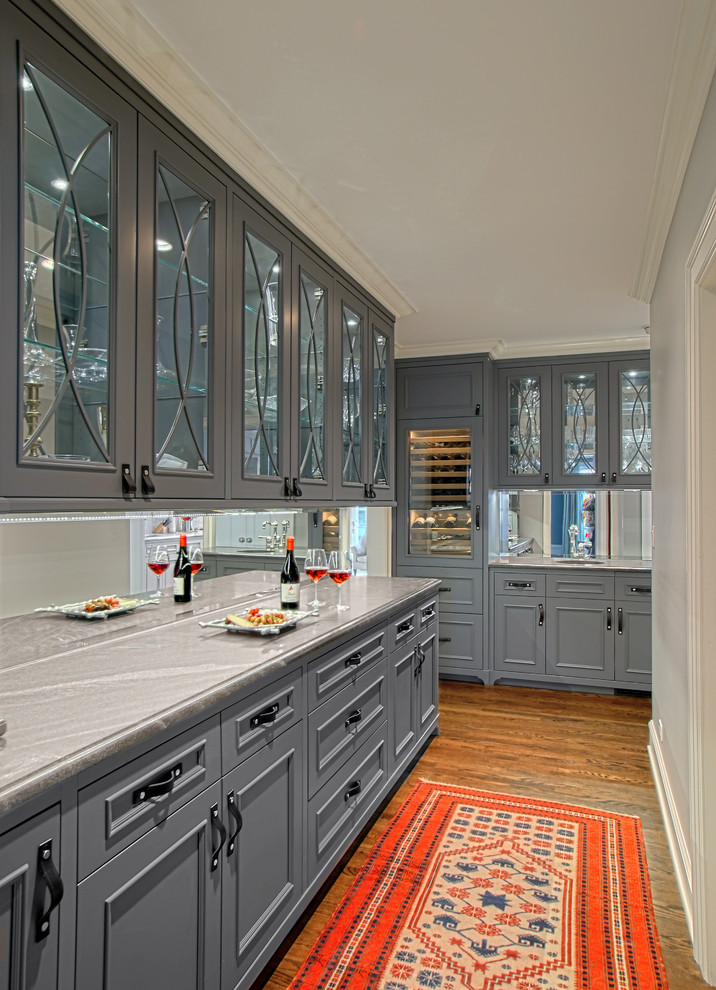 Idée de décoration pour une cuisine tradition avec une crédence miroir, des portes de placard grises, un plan de travail en quartz et un plan de travail gris.
