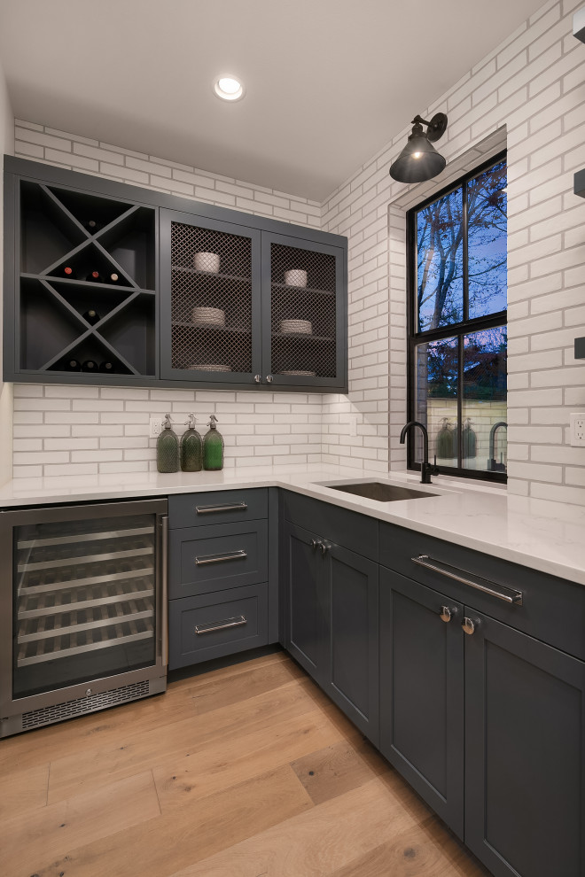 Design ideas for a large farmhouse home bar in Seattle with shaker cabinets, grey cabinets, white splashback, brick splashback, medium hardwood flooring and white worktops.
