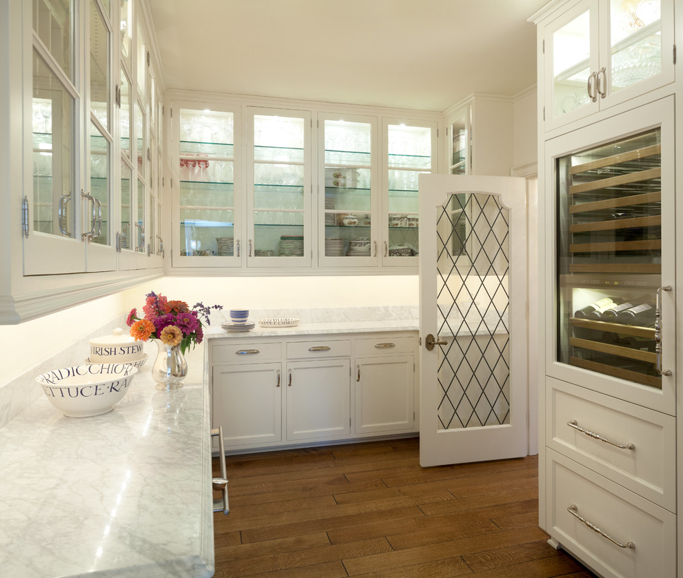Mid-sized elegant kitchen pantry photo in Minneapolis with glass-front cabinets, white cabinets and marble countertops