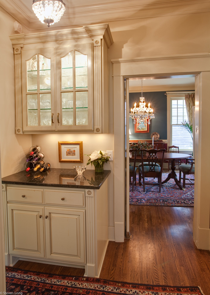 Idée de décoration pour une cuisine américaine linéaire tradition en bois vieilli avec un placard avec porte à panneau surélevé, un plan de travail en granite et une crédence beige.