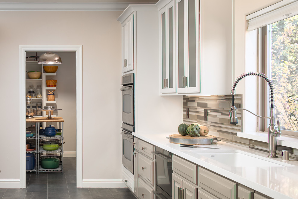 Inspiration for a large contemporary galley ceramic tile and gray floor eat-in kitchen remodel in Sacramento with a drop-in sink, glass-front cabinets, white cabinets, quartz countertops, multicolored backsplash, glass tile backsplash, stainless steel appliances and an island