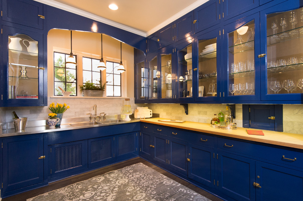 Inspiration for a mid-sized transitional l-shaped medium tone wood floor kitchen pantry remodel in Chicago with an integrated sink, shaker cabinets, blue cabinets, wood countertops, white backsplash and subway tile backsplash