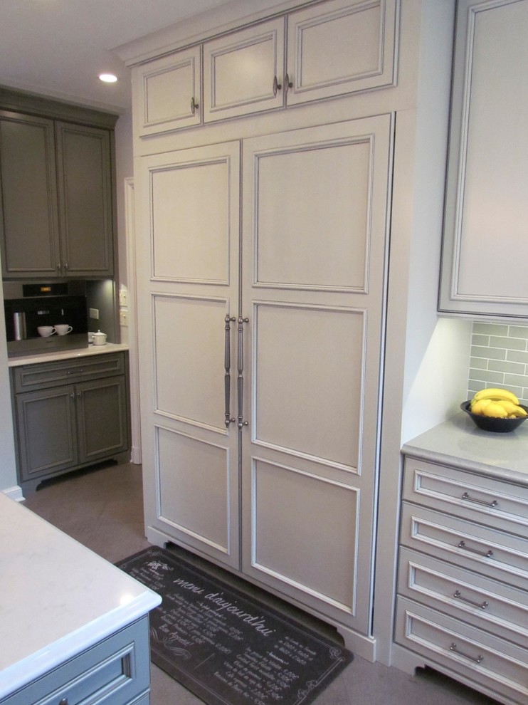 Inredning av ett klassiskt stort l-kök, med en rustik diskho, luckor med infälld panel, vita skåp, bänkskiva i kvarts, grått stänkskydd, stänkskydd i keramik, klinkergolv i porslin och en köksö
