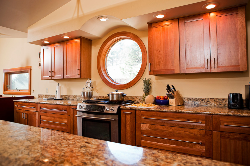Exemple d'une cuisine parallèle tendance en bois brun avec un plan de travail en granite, une crédence marron, une crédence en dalle de pierre et un électroménager en acier inoxydable.
