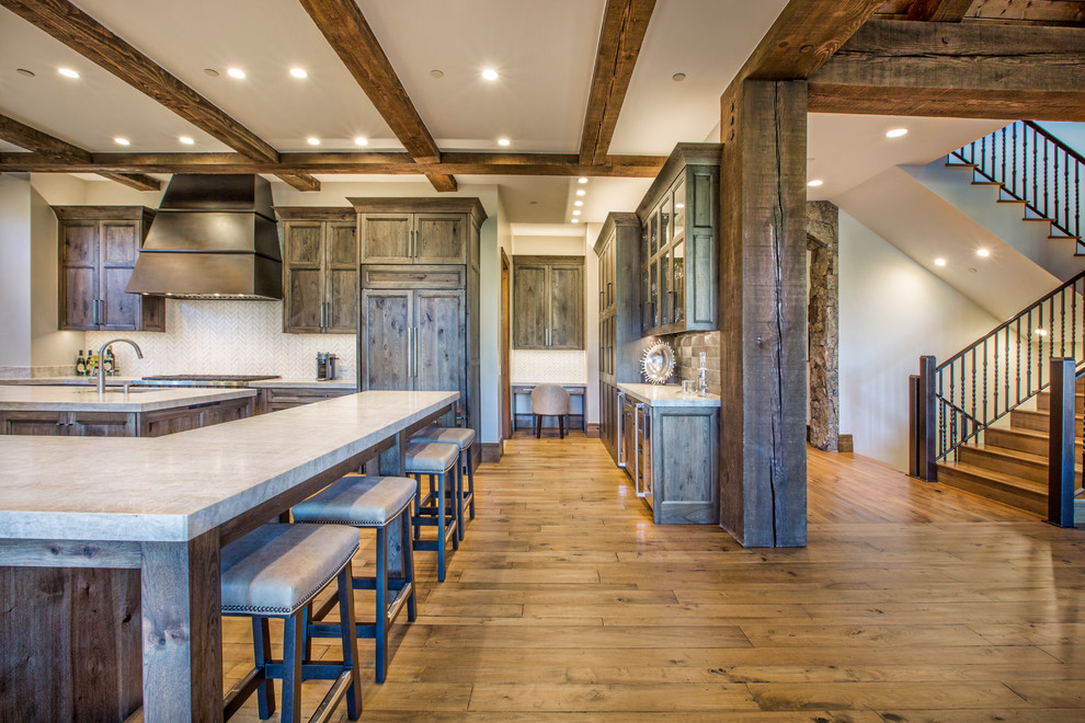 Design ideas for a large rustic l-shaped kitchen/diner in Denver with a submerged sink, shaker cabinets, distressed cabinets, laminate countertops, white splashback, mosaic tiled splashback, integrated appliances, light hardwood flooring, multiple islands and brown floors.