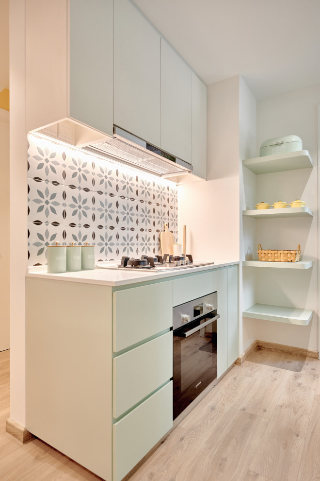 Inspiration for a small scandinavian single-wall kitchen in Singapore with flat-panel cabinets, green cabinets, multi-coloured splashback, mosaic tiled splashback, light hardwood flooring, no island, beige floors and white worktops.