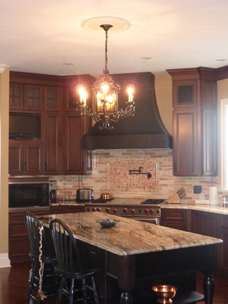 Ejemplo de cocina comedor clásica con armarios con paneles empotrados, puertas de armario de madera en tonos medios, encimera de granito y electrodomésticos con paneles