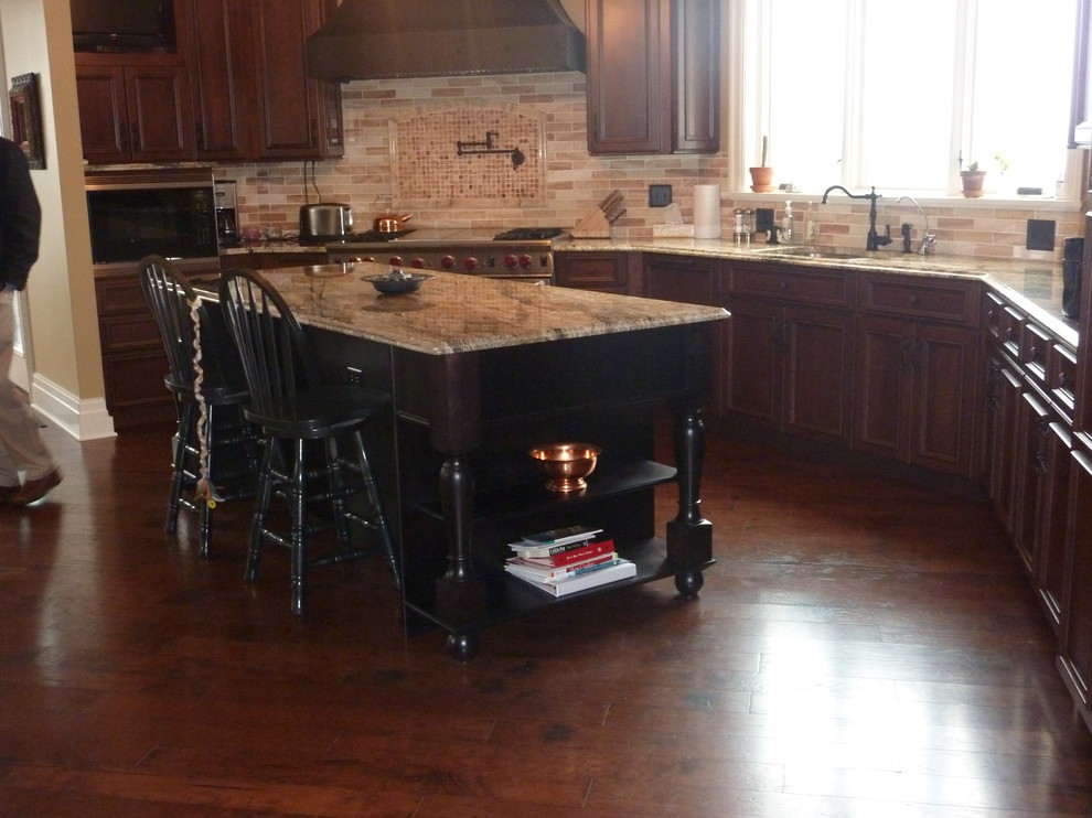 Example of a classic eat-in kitchen design in St Louis with recessed-panel cabinets, dark wood cabinets, granite countertops and paneled appliances