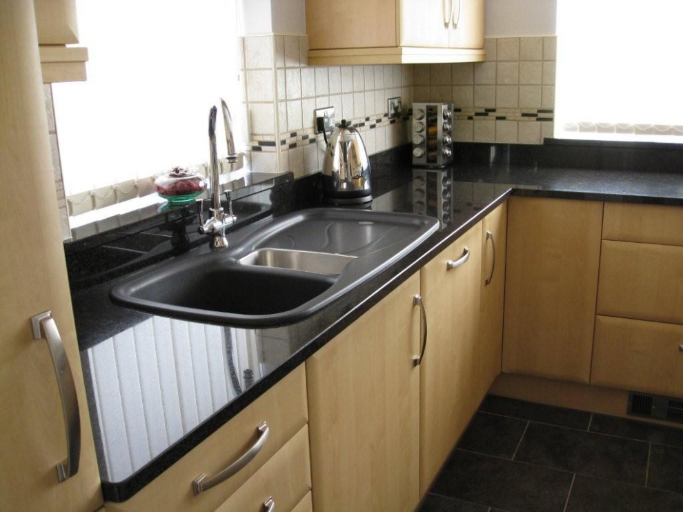 Example of a farmhouse kitchen design in London with granite countertops and black countertops