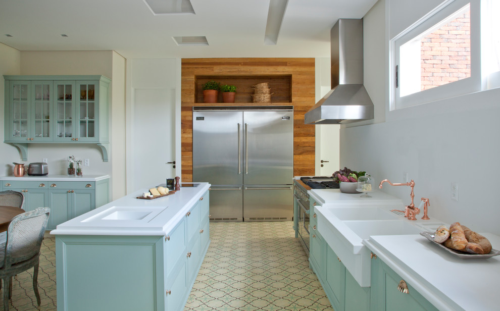 Traditional u-shaped kitchen/diner in Other with a double-bowl sink, recessed-panel cabinets, green cabinets, white splashback, stainless steel appliances, an island, beige floors and white worktops.