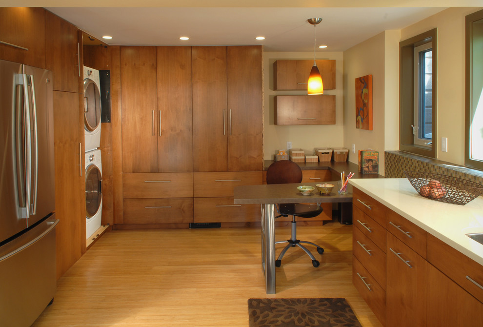 Moderne Küche mit Küchengeräten aus Edelstahl, flächenbündigen Schrankfronten und hellbraunen Holzschränken in Sonstige